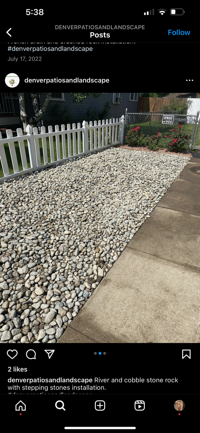 White decorative rocks beside a concrete walkway and white picket fence in a garden area