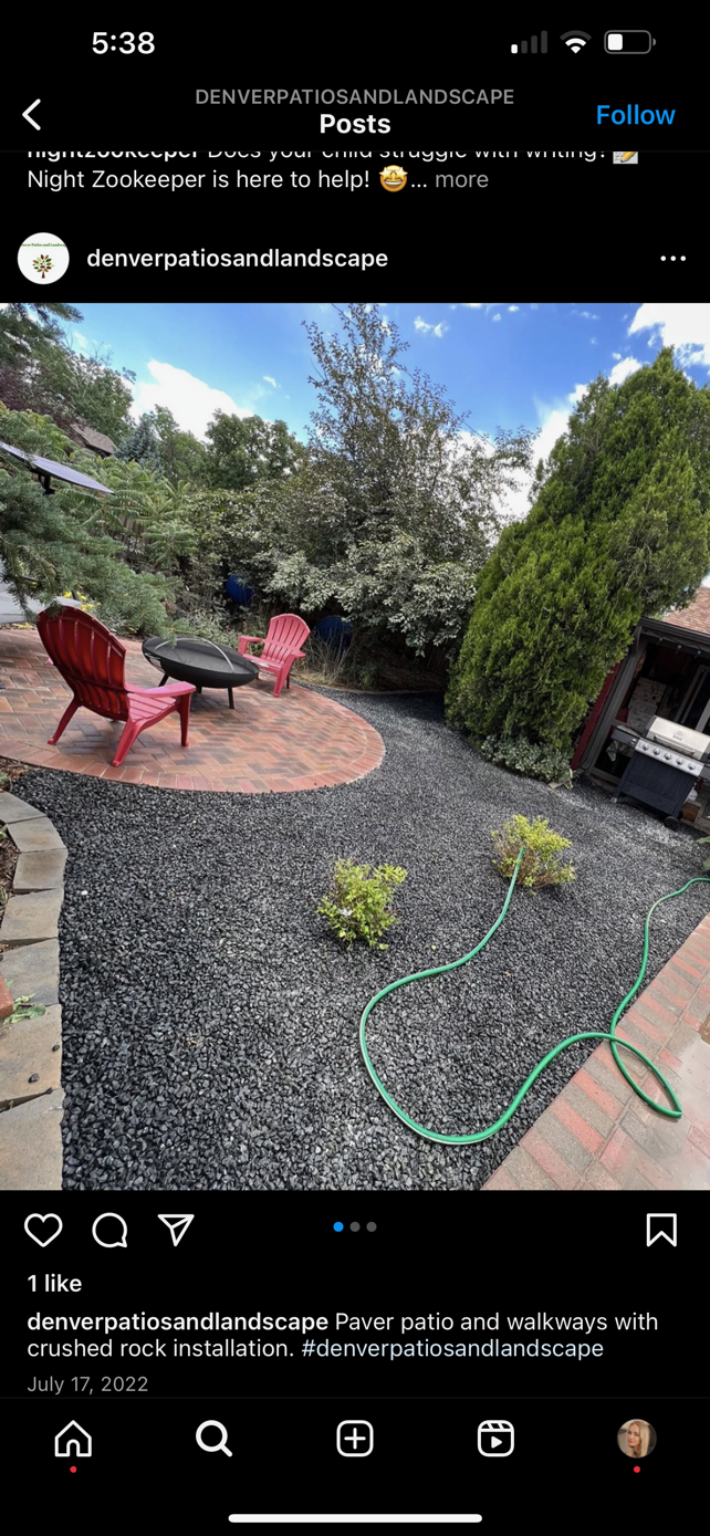 Backyard patio with red chairs, gravel, potted plants, and a green garden hose.