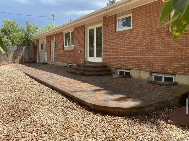 Brick house backyard with a curved paved patio and gravel ground under a sunny sky