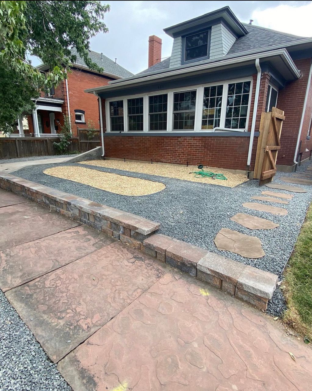 Front of a brick house with gravel landscaping, stone pavers, and a sloped driveway