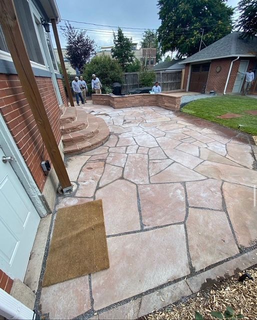 Stone-paver backyard patio with steps, brick house, and two people near the walkway