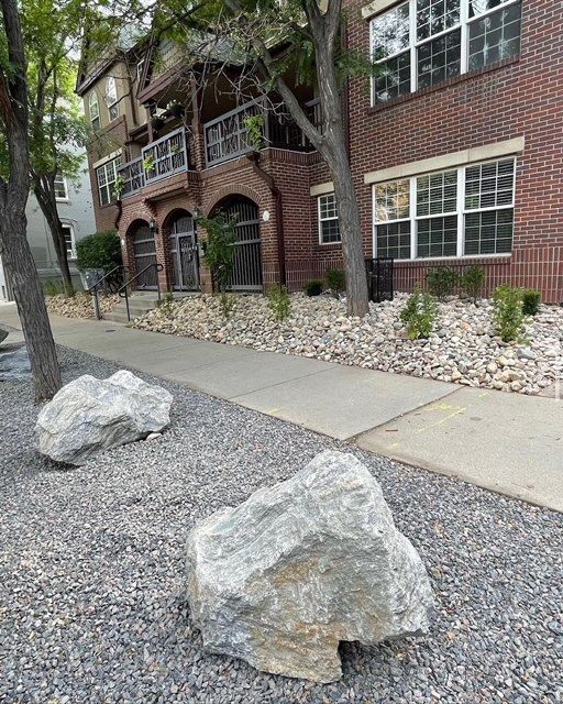 Brick apartment building with gravel landscaping, concrete sidewalk, and large decorative rocks