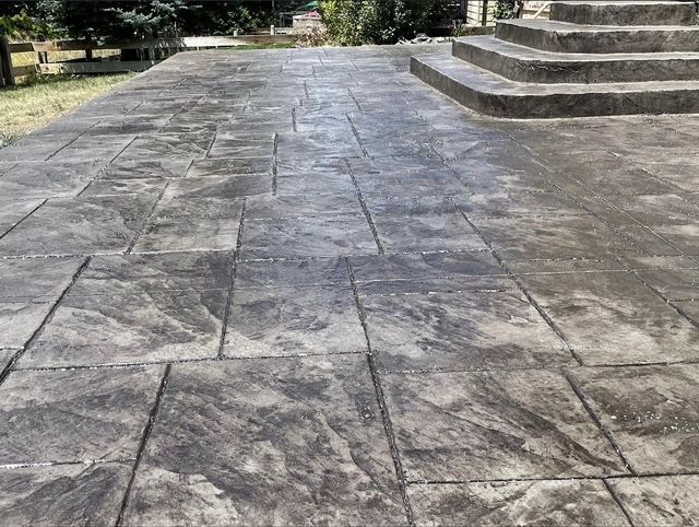 Stone plaza with large gray pavers and steps on the right, viewed in an outdoor park setting